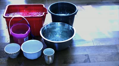 stock-footage-buckets-on-the-floor-catch-water-leaking-in-from-the-ceiling-and-roof-on-a-night-with-lighting-and